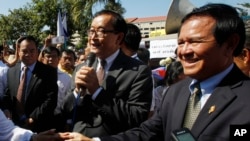 Opposition leader of Cambodia National Rescue Party Sam Rainsy, center, delivers a speech next to his Deputy President Kem Sokha, right, during a gathering to mark Human Rights Day, in front of National Assembly, in Phnom Penh, Cambodia, Wednesday, Dec. 10, 2014. (AP Photo/Heng Sinith) 