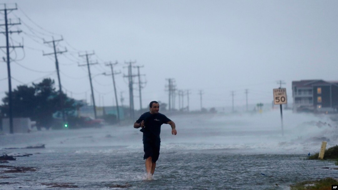 Un sujeto cruza la carretera mientras el huracán Arthur golpea a Carolina del Norte este 4 de julio.