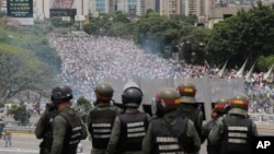 In this May 3, 2017 photo, Bolivarian National Guards stand on a highway overlooking an anti-government march trying to make its way to the National Assembly in Caracas, Venezuela.