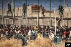 Polisi anti huru hara menutup kawasan, setelah para migran tiba di tanah Spanyol dengan melintasi pagar yang memisahkan kantong Spanyol Melilla dari Maroko di Melilla, Spanyol, Jumat, 24 Juni 2022. (AP/Javier Bernardo)
