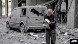 Seorang pria Palestina membaca buku di depan sebuah mobil yang rusak akibat serangan udara Israel di Kota Gaza, 3 Maret 2024. (Foto: AFP)