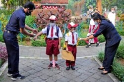 Petugas memeriksa suhu tubuh siswa pada hari pertama pembukaan kembali sekolah di Jakarta, Senin, 30 Agustus 2021. (Foto: AP)