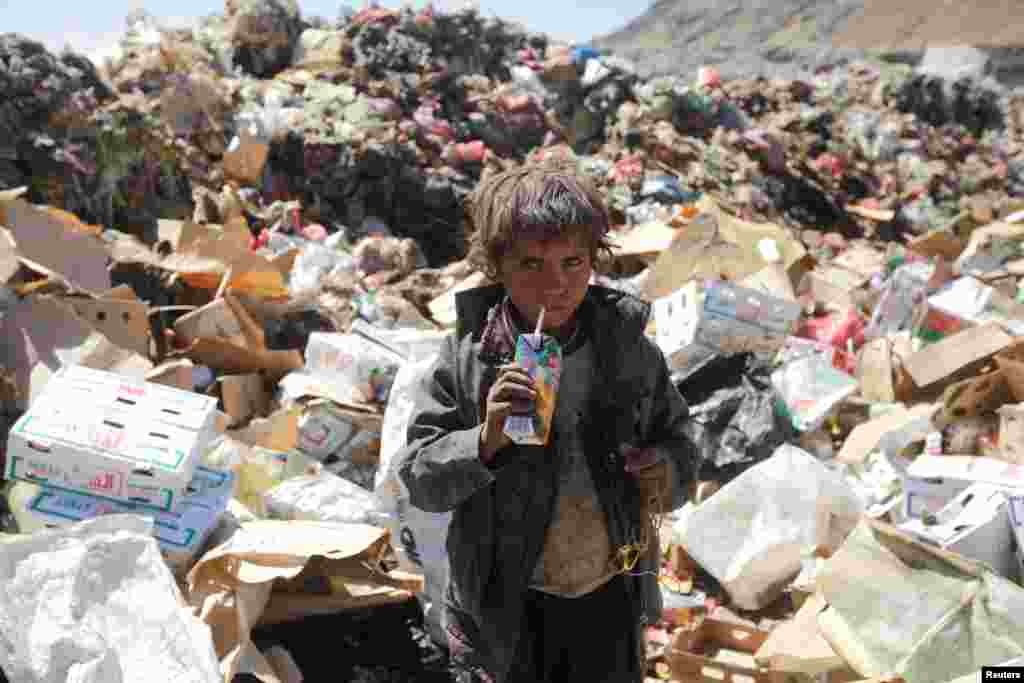 A boy drinks expired juice on a pile of rubbish at a landfill site on the outskirts of Sana'a, Yemen.