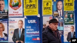 Një banor në Bukuresht kalon përmes stendave me postera zgjedhorë
