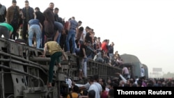 People gather at the site where train carriages derailed in Qalioubia province, north of Cairo, Egypt, April 18, 2021.
