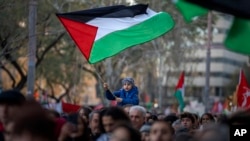 Seorang anak laki-laki mengibarkan bendera Palestina di tengah demonstrasi mendukung warga Palestina dan menyerukan gencatan senjata segera di Gaza, di Barcelona, Spanyol, 20 Januari 2024. (Foto: AP)