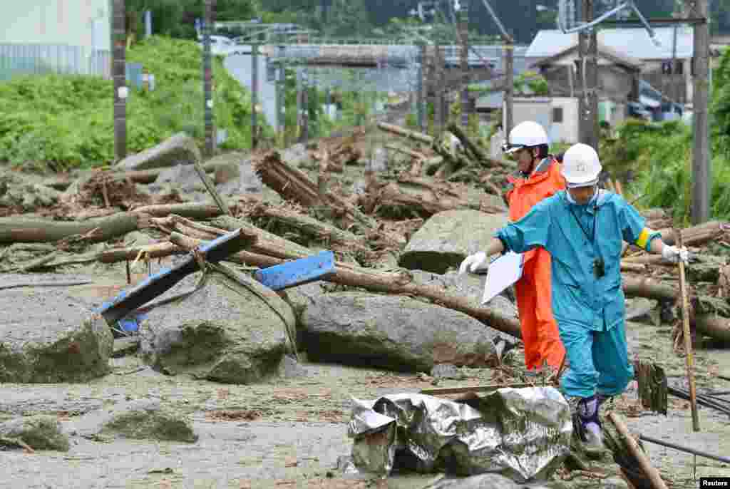 Workers walk among debris after a landslide caused by heavy rains due to Typhoon Neoguri in Nagiso town, Nagano prefecture, in this photo taken by Kyodo, July 10, 2014.