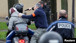Policías frances arrestan a dos jóvenes en una motocicleta cuando se acercaban a la zona donde un atacante ha tomado rehenes en un supermercado judío en el este de París.