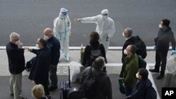 Un agent chinois dirige les membres de l'équipe de l'OMS à leur arrivée à l'aéroport de Wuhan, dans la province de Hubei, en Chine centrale, le jeudi 14 janvier 2021.