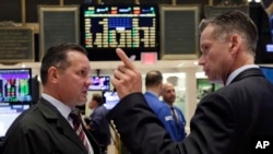 Traders on the floor of the New York Stock Exchange react to market changes, Aug. 25, 2015.