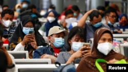 Penumpang duduk di stasiun kereta sambil menunggu untuk kembali ke kampung halaman menjelang perayaan Idul Fitri, sebuah kegiatan yang dikenal dengan sebutan "mudik", di tengah pandemi COVID-19, di Jakarta, 5 Mei 2021. (Foto: Reuters)