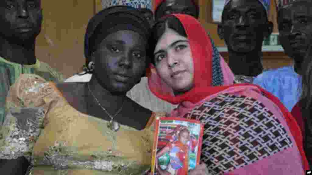 La défenseuse pakistanaise de l’éducation pour jeunes filles, Malala Yousafzai, tient la photo d’une écolière enlevée, Sarah Samuel, avec la mère de la victime, à Abudja, Nigeria, le 13 juillet 2014. (AP Photo/Olamikan Gbemiga)