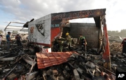 Firefighters and rescue workers remove debris from the scorched ground of Mexico's best-known fireworks market after an explosion explosion ripped through it, in Tultepec, on the outskirts of Mexico City, Mexico, Dec. 20, 2016.