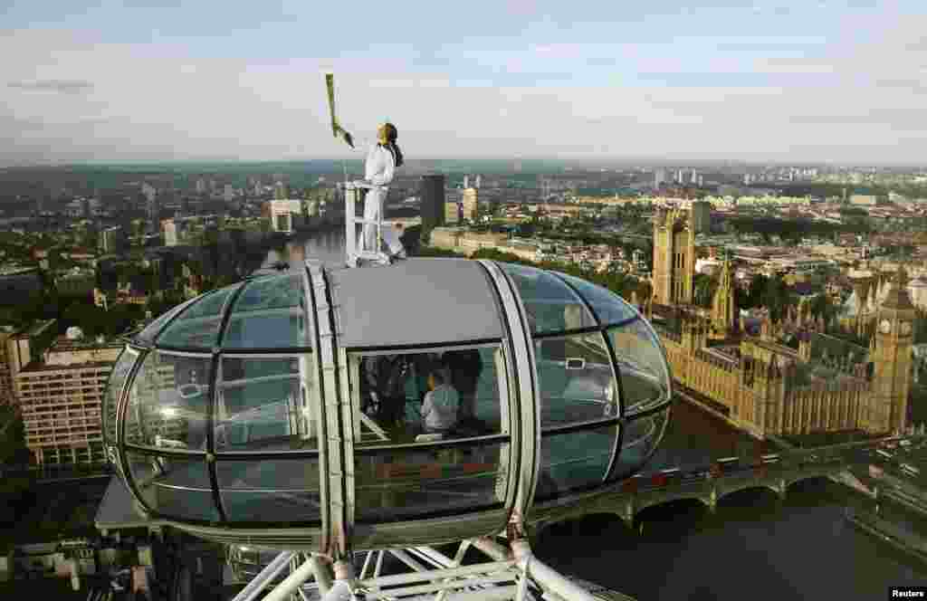 Torch bearer Amelia Hempleman-Adams, 17, stands on top of a capsule on the London Eye as part of the torch relay ahead of the London 2012 Olympic Games in London July 22, 2012.