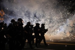 FILE - Police advance on protesters to clear a street on the 100th consecutive night of protests against police violence and racial inequality, in Portland, Oregon, Sept. 5, 2020.