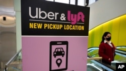 Seorang pejalan kaki melintas di depan papan layanan transportasi daring Uber dan Lyft di Bandara Internasional Logan, di Boston, Massachusetts, 9 Februari 2021.
