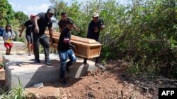 Hombres trasladan el ataúd de un minero fallecido por el colapso de una mina ilegal, durante su entierro en La Paragua, Bolívar, este 22 de febrero de 2024.