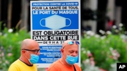 Ljudi nose zaštitne maske prlazeći pored obavještenja o obaveznom nošenju maski i na ulici, u Bayonneu, jugozapadna Francuska, 28. jula 2021.
