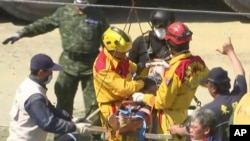 In this image made from video, Lee Tsung-tien, 42, is attended to by rescue workers after he was pulled out conscious from a building which collapsed after an earthquake in Tainan, Taiwan, Monday, Feb. 8, 2016.