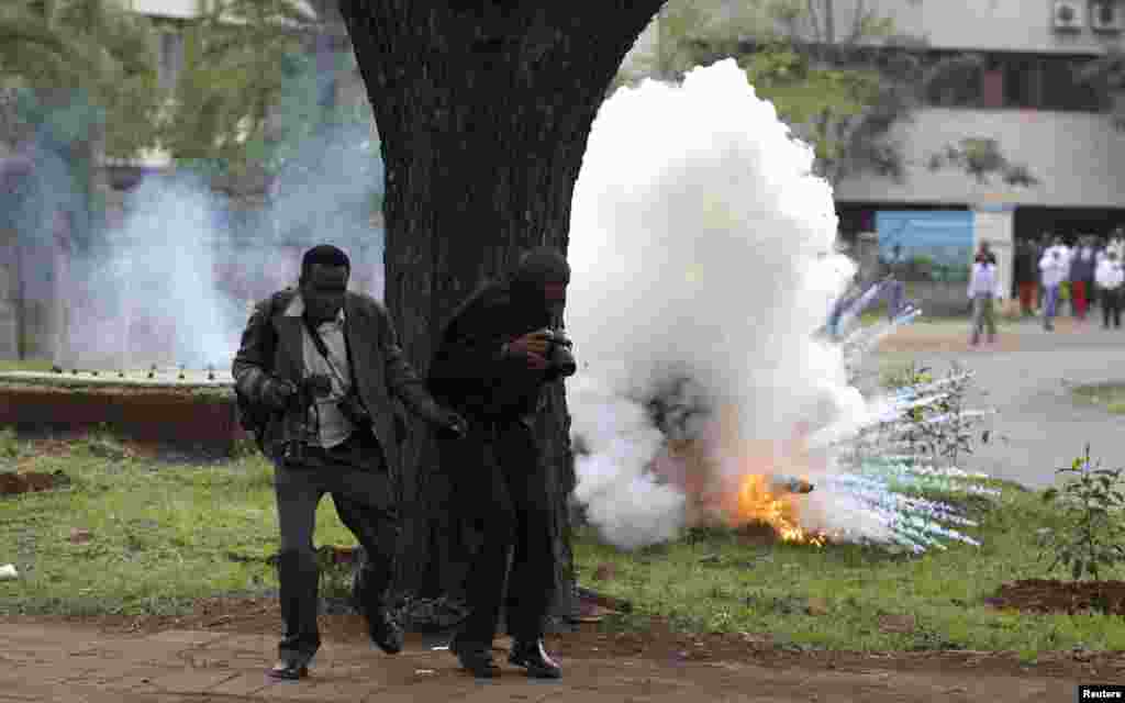 Dua wartawan foto menghindar dari gas air mata yang dilemparkan oleh polisi anti huru-hara untuk membubarkan demonstrasi mahasiswa di Nairobi, Kenya. 