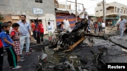 Warga berkumpul di lokasi ledakan bom bunuh diri di distrik Kamaliya, Baghdad, Senin (20/5). Serangan di Baghdad menewaskan sedikitnya 48 orang. 