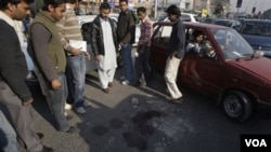 Warga di Lahore, Pakistan melihat tumpahan darah di lokasi insiden penembakan antara seorang diplomat AS dan dua penyerangnya, Kamis 27 Januari 2011.