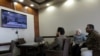 Men watch the elections to choose the new interim government on a TV screen at a cafe in Benghazi, Libya, Feb., 5, 2021.