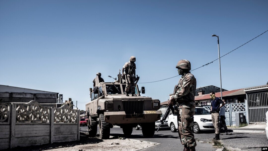 South African National Defense Force (SANDF) soldiers stand next to an Armored Personnel Carrier in the Cape Flats area of Cape Town, on March 30, 2020, during a patrol to enforce a nationwide lockdown. 