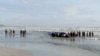 Orang-orang melakukan pencarian korban di pantai Tanjung Balau setelah sebuah kapal yang membawa para migran terbalik, di Kota Tinggi, Johor, Malaysia, 15 Desember 2021. (Royal Malaysian Army/Handout via REUTERS)