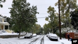 Para pejalan kaki berjalan di jalanan yang terkubur salju di Helena, Montana, 29 September 2019. (Foto: AP) 