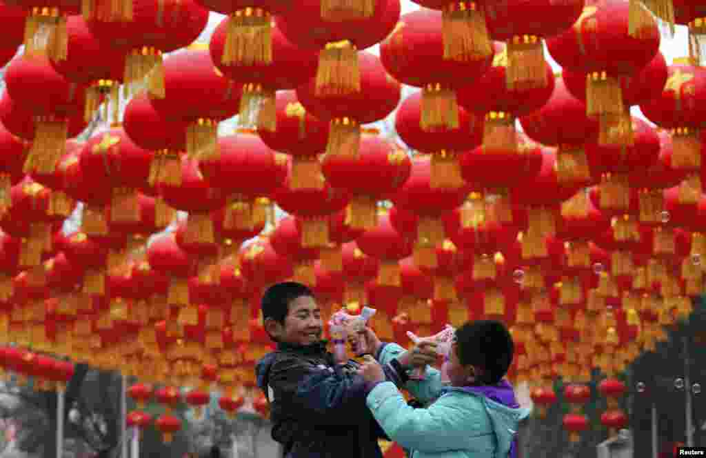 Anak-anak bermain dengan pestol-pestolan air di bawah dekorasi tahun baru Imlek di sebuah taman di Beijing. Menurut penanggalan China, tahun baru China yang merupakan tahun kuda, jatuh pada tanggal 31 Januari.