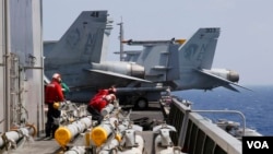 美國海軍卡爾·文森航空母艦上的人員在F-18戰機例行出航前準備為飛機加裝導彈。（2017年3月3日）
