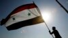 A Syrian protester stands on top of a building as he waves a Syrian flag, during a demonstration against a U.S. raid at a village near the Syrian-Iraqi border, in Damascus, Syria, Oct. 30, 2008. Hundreds of Syrian riot police ringed the shuttered and clos