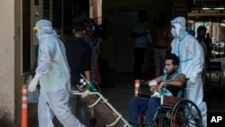 Health workers in protective suits shift a COVID-19 patient at a government hospital in Gauhati, India, May 24, 2021.