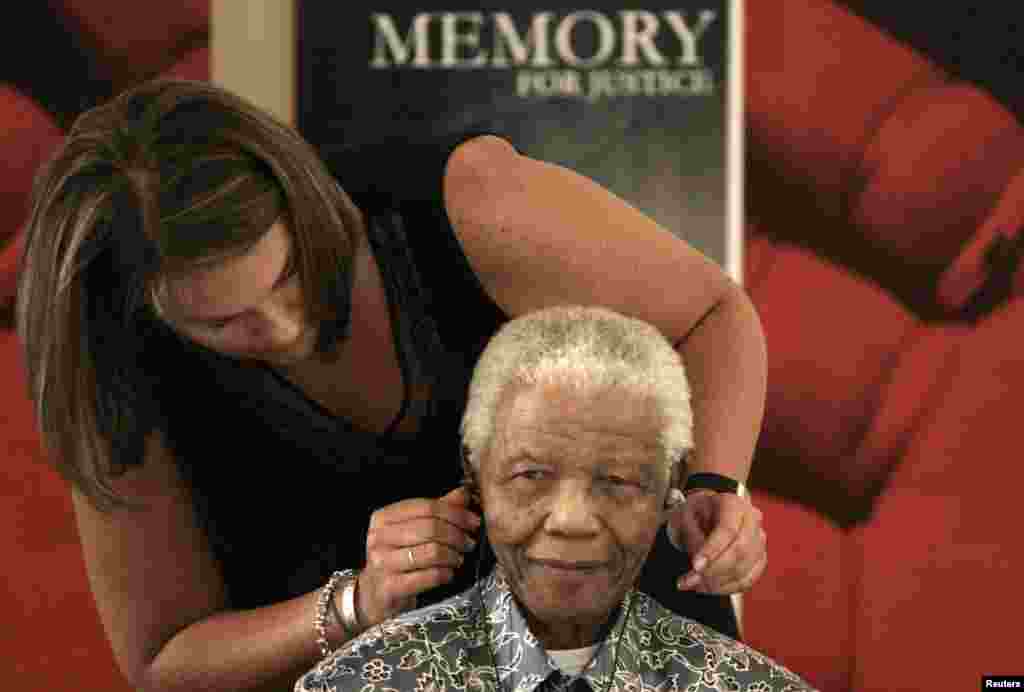L'ancien président sud-africain Nelson Mandela assisté par Zelda la Grange qui l'aide à ajuster son aide auditive lors de son acceptation de collections historiques des Archives nationales à la base Mandela à Houghton, le 28 Novembre 2008.