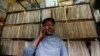 FILE - Vendor James Rugami talks to a customer on his cell phone inside his shop that specialize in selling second-hand vinyl records and vintage players at the Kenyatta Market in Nairobi, Nov. 24, 2016. 