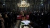Seorang wanita mencium layar pelindung di atas peti mati Patriark Irinej saat dia berbaring di gereja Kongregasional di Beograd, Serbia, Sabtu, 21 November 2020. (Foto: AP)