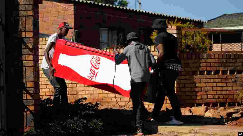 Des manifestants transportent un réfrigérateur Coca Cola qu'ils ont pillé dans un magasin, lors des manifestations à Atteridgeville, en Afrique du Sud, le 21 juin 2016.