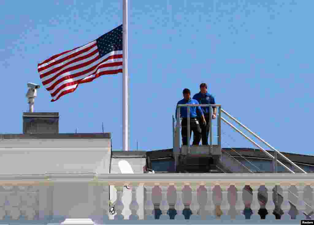 White House staff are pictured after they lowered the U.S. flag to half staff on the roof of the White House in Washington, September 12, 2012, following the death of U.S. Ambassador to Libya, Chris Stevens.