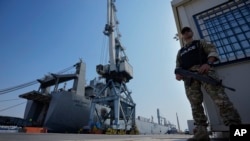 FILE - A Cypriot military police officer stands guards next of the docked U.S ship carrying Gaza aid, at the port of Larnaca, Cyprus, June 26, 2024.