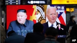 FILE - Commuters watch a TV showing a file image of North Korean leader Kim Jong Un and U.S. President Joe Biden during a news program at the Suseo Railway Station in Seoul, South Korea, March 26, 2021. 
