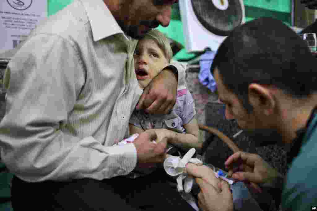 A Syrian child reacts while being treated by a doctor, in a hospital in Aleppo, Syria, September 11, 2012.