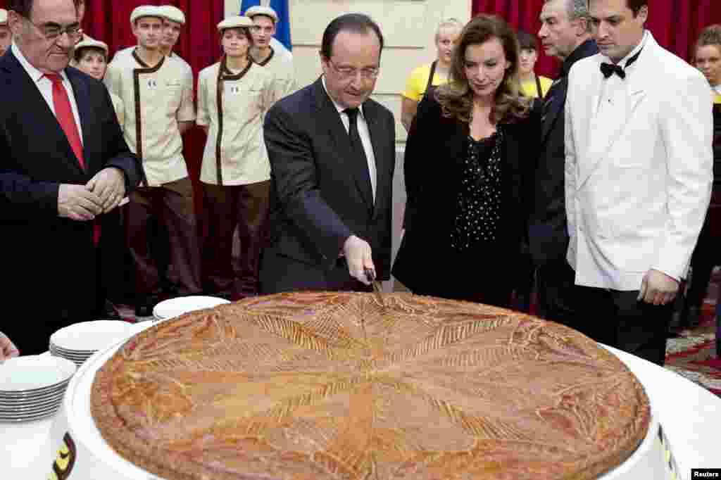 Presiden Perancis Francois Hollande (tengah) memotong kue tradisional 'Epiphany' dalam upacara di istana Elysee, Paris.