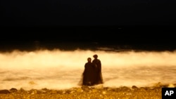 FILE - two veiled Saudi women enjoy the Red Sea at night, in Jiddah, Saudi Arabia, Dec. 26, 2007. Saudi Arabia is planning to build a semi-autonomous luxury travel destination along its Red Sea coast that visitors can reach without a visa. The Red Sea area, which will include diving attractions and a nature reserve, will be developed with seed capital from the country's Public Investment Fund.