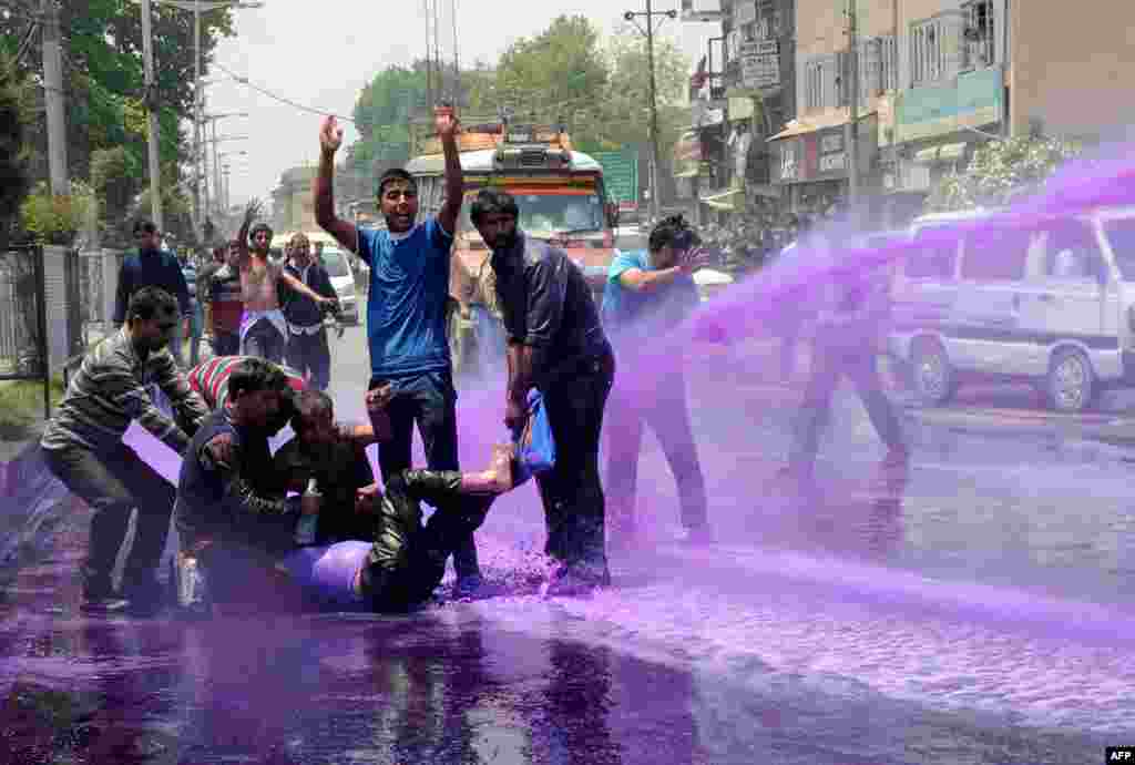 Pegawai pemerintah di Kashmir yang melakukan unjuk rasa terkena semprotan air berwarna ungu dari pasukan anti huru-hara di Srinagar, Kashmir-India.