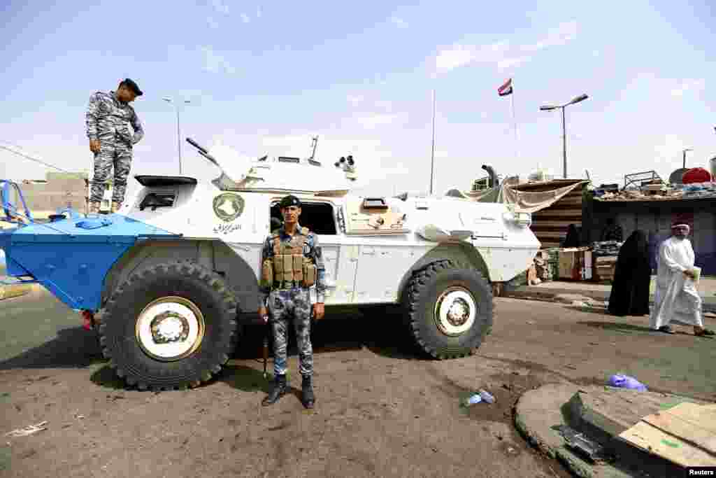 Iraqi security forces stand guard at the site of a car bomb attack in the New Baghdad neighborhood, Aug. 26, 2014.