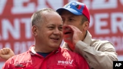 Pemimpin Partai Sosialis Venezuela Diosdado Cabello, kiri, mendengarkan bisikan Wakil Presiden Venezuela Tareck El Aissami saat protes menentang AS di Caracas, Venezuela, 28 Maret 2017.