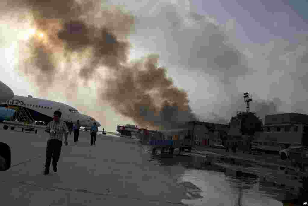 Smoke rises above the Jinnah International Airport where security forces continue to battle militants in Karachi, Pakistan, June 8, 2014. Gunmen disguised as police guards attacked a terminal with machine guns and a rocket launcher during a five-hour siege that killed at least 28 people as explosions echoed into the night, while security forces retaliated and killed all the attackers, officials said.