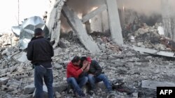 A Syrian man comforts another on the rubble of a building after a reported Russian airstrike on a popular market in the village of Balyun in Syria's northwestern Idlib province, Dec. 7, 2019.