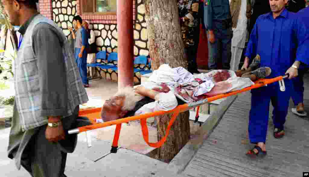 Afghan men carry an injured man to a hospital after a suicide attack in Faryab province, north of Kabul, July 22, 2015.